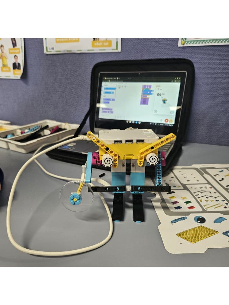 A robotic device plugged into a laptop positioned on a desk.