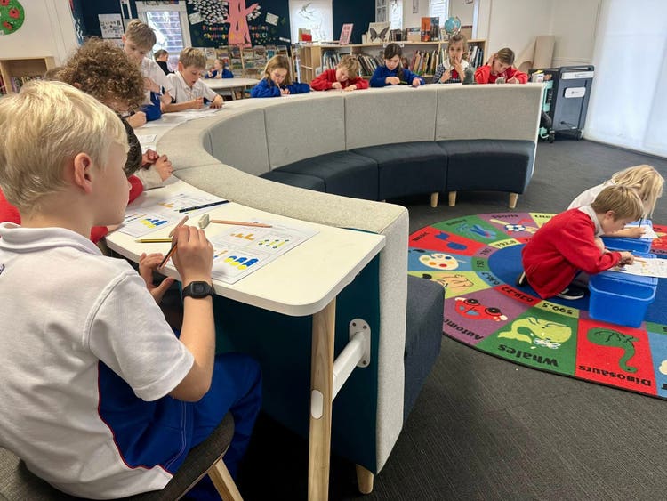 A groups of students seated at a circular table in a school library working.