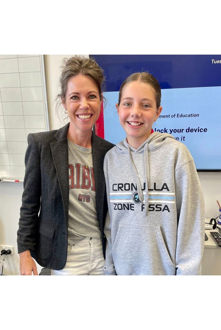 A lady and student standing side by side smiling at the camera.