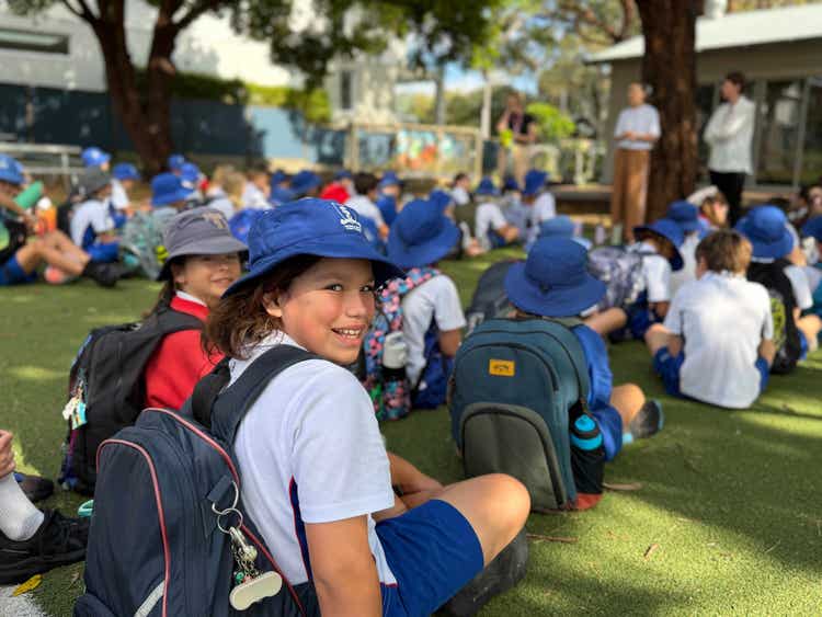 Student looking at the camera during class lines during the morning. Two teachers in the background.