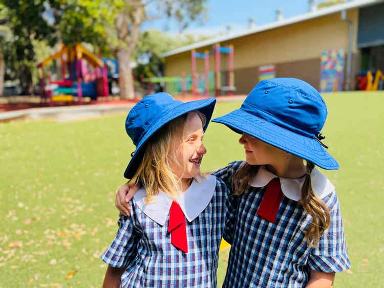 Two children on the school playground looking and smiling at each other.