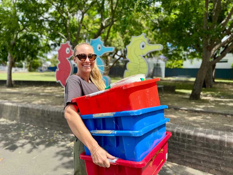 image of a parent volunteer carrying lunch order tubs